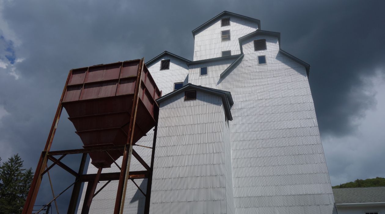 The seven story Maxon Mills wooden grain elevator, which has been repurposed into an art gallery for the Wassaic Project, is stark white and foreboding against a background of ominous black clouds.